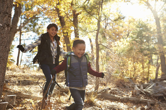 Two Hispanic Children Have Fun Running In A Forest