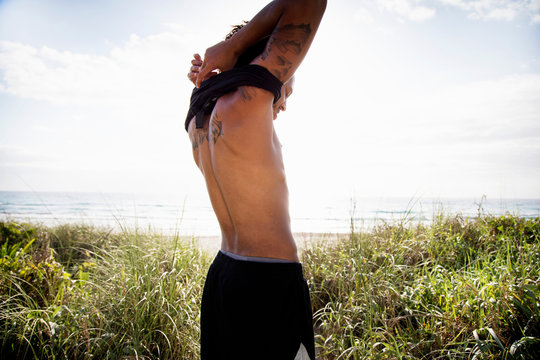Man removing singlet by ocean