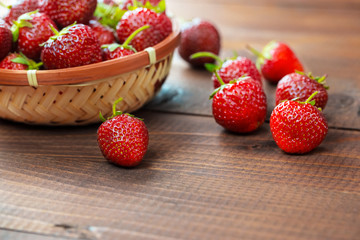 Very beautiful background with fresh strawberries in a wicker round osier basket on old brown wooden background