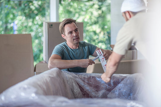Moving house: two men wrapping sofa in bubble wrap