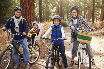 Fototapeta na wymiar Portrait of an Asian family on bikes in a forest, close up