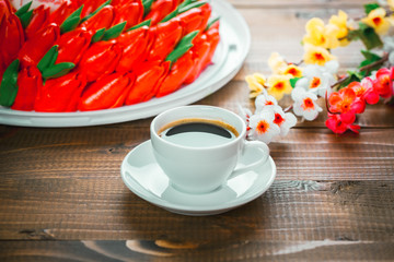 Beautiful background with a Cup of hot coffee with foam and a birthday cake with flowers on wooden background