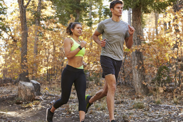 Caucasian woman and man running on a forest trail, close up