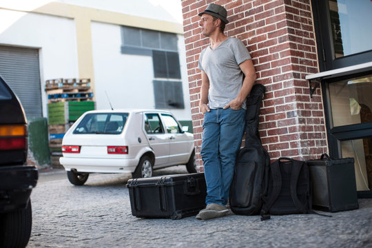 Street musician with musical equipment, standing, leaning against wall