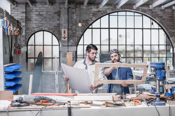 Craftsmen inspecting frame in antique restoration workshop