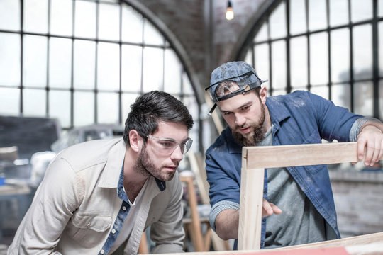 Craftsmen inspecting frame in antique restoration workshop