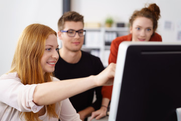 junge frau zeigt ihren kollegen etwas am pc