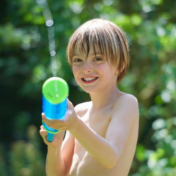 Portrait of boy squirting water gun in garden