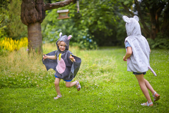 Two young sisters wearing mouse costume running in garden