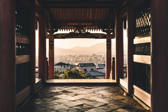 Through old and new - City view framed by ancient pagoda at sunset.