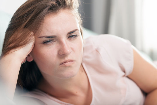 Young woman lying on couch and she is angry. Casual style indoor shoot