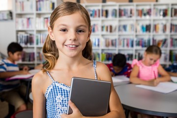 A cute little girl smiling at the camera with tablet pc 