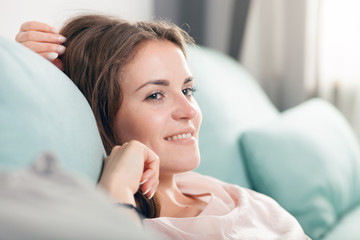 Happy young woman lying on couch and relaxing at home. Casual style indoor shoot