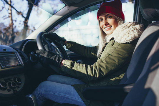 Portrait of happy young woman in warm clothing driving car
