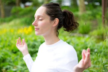 Obraz premium View of a Young attractive woman practising yoga in a park