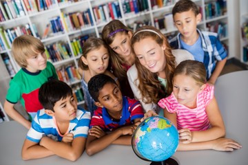 Teacher and pupils looking at a globe 