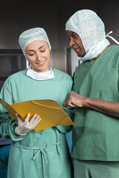 Two surgeons in scrubs consulting over a medical file