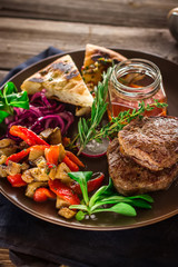 Fried meat with vegetables and sauce on the plate.
