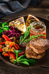 Fried meat with vegetables and sauce on the plate.