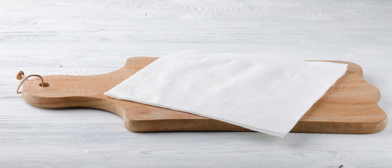 Wooden board with white napkin on the table.