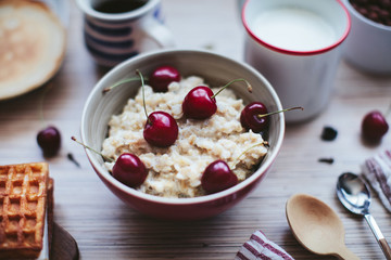 rich breakfast of porridge with cherries and pastry