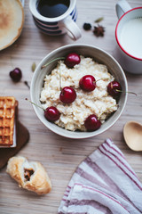 rich breakfast of porridge with cherries and pastry