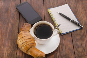 breakfast with cup of black coffee, croissants and notebook