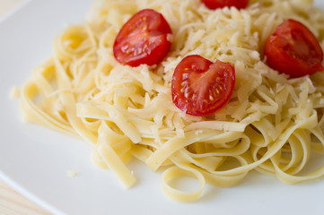 Italian pasta with cheese and cherry tomatoes on a white plate