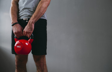Midsection of man lifting kettlebell at gym