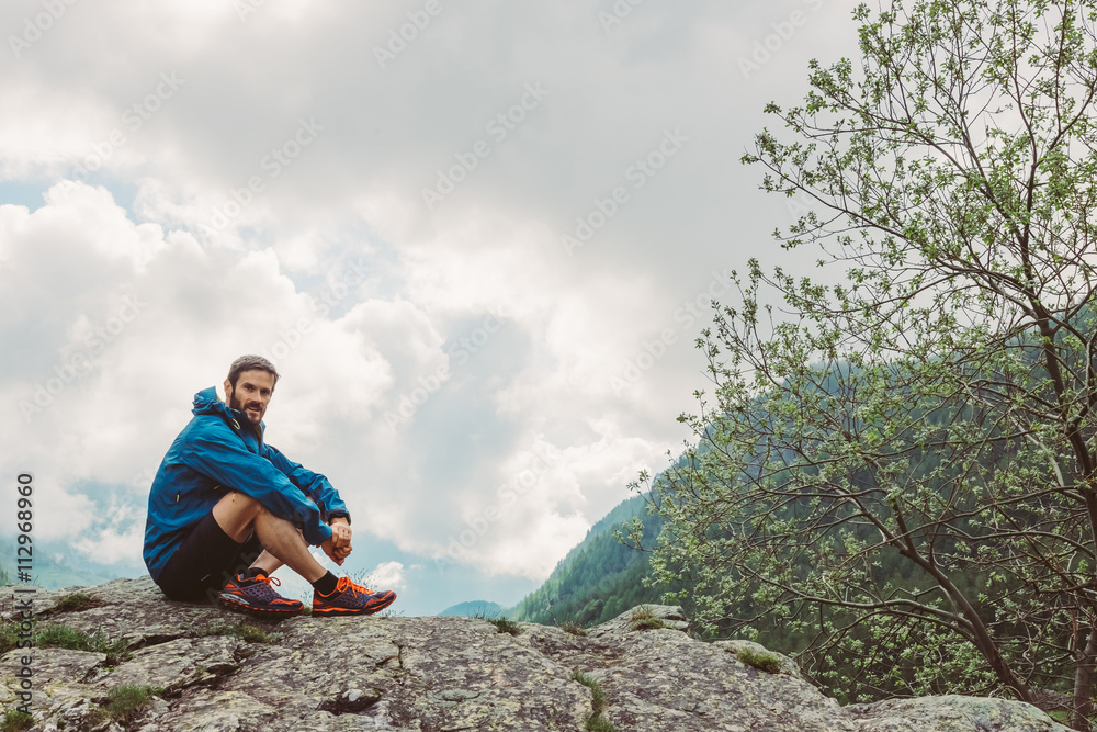 Wall mural man at the top of a mountain looking the landscape