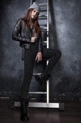 Fashion shot beautiful sexy girl in jeans and leather jacket on ladder