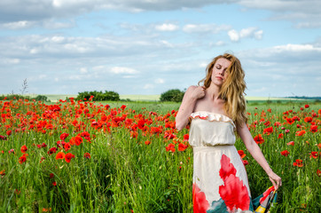 Young beautiful happy girl with long hair in a white dress in the poppy field with a wreath on his head