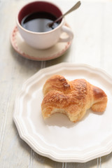 Bited croissant and coffee cup
