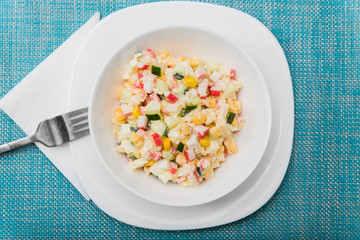 Crab salad in a plate on a blue tablecloth, top view