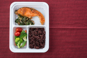 Food series : Grilled salmon, served with rice berry and fresh vegetable in plastic box, Thai foods
