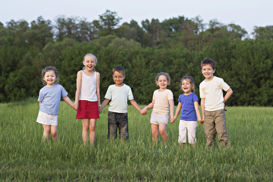 Children holding hands and standing in a field