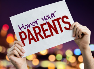 Honor Your Parents placard with night lights on background