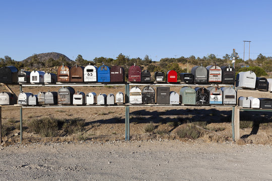 Rows of mailboxes next to a dirt road in a desert