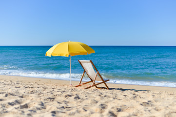 Yellow umbrella and wooden chair on Atlantic sandy beach