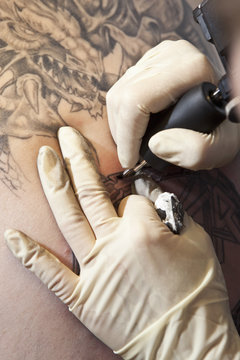Close-up of a tattoo artist tattooing a design on human skin