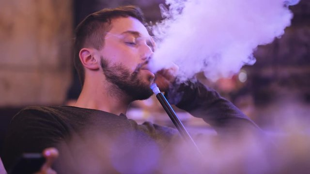 handsome man smokes hookah in the bar