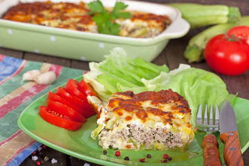 Moussaka in casserole dish and slice of moussaka on a green plate
