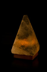 Salt lamp glowing in the form of a pyramid in the darkness