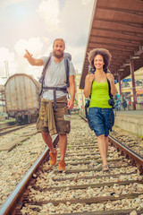 Happy and beautiful couple of tourists walking on the tracks at