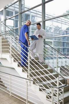 Two medical workers looking at a chart on a staircase