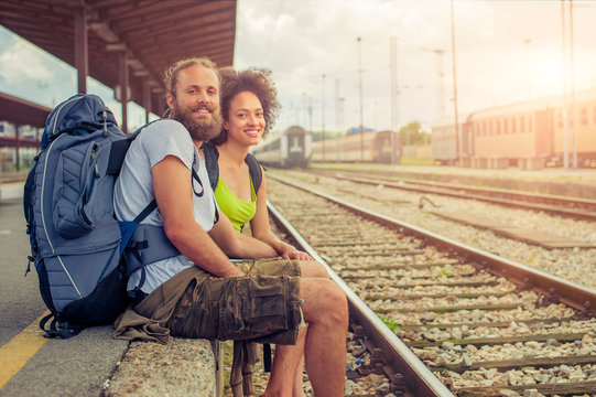 Happy young and beautiful couple of tourists sitting at the rail