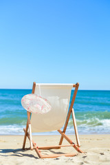 Deckchair and female hat on stunning tropical beach vacation background