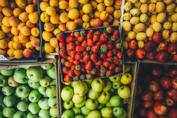 ripe juicy fruits and berries are in cardboard boxes summer day on the market. top view