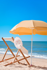 Sun parasol, chair longue and female hat on vacation beach sun shine 