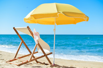 Sun parasol, chair longue and female hat on vacation beach sun shine 